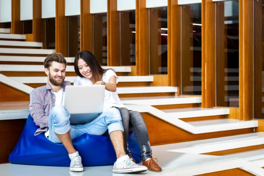 A man and a woman on a bean bag looking at a computer